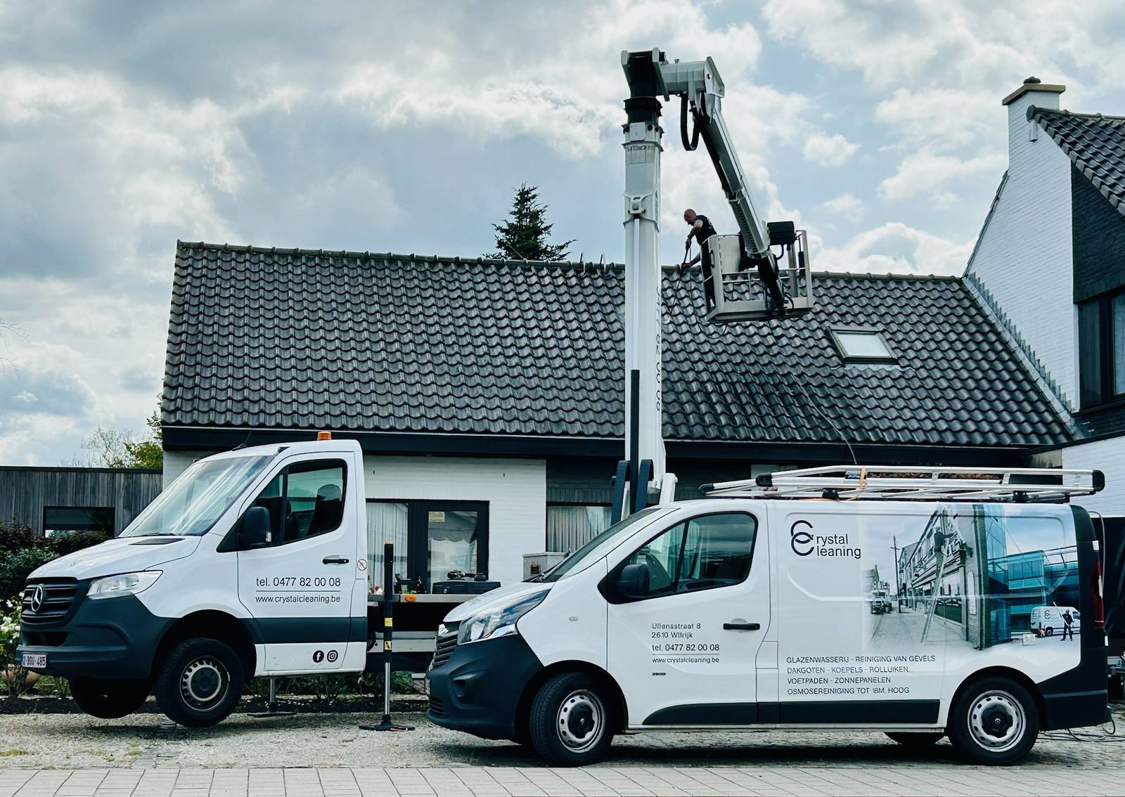 Twee bestelwagens van Crystal Cleaning en een hoogtewerker aan een woning