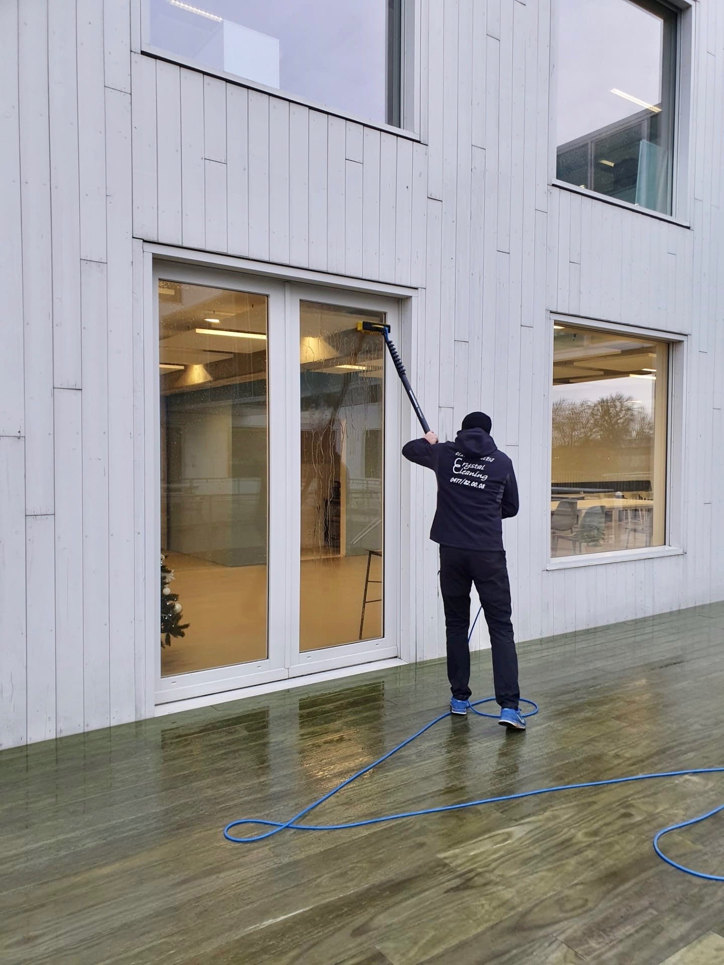 Medewerker die ramen reinigt met een telescoopstang